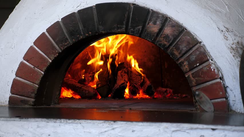 Close-up firewood is burning in a traditional italian pizza oven. Hot coals in the oven in an old pizzeria. 