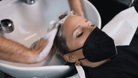 An experienced hairdresser creates a hairstyle for a beautiful young woman after cutting and coloring her hair. She is wearing protective face mask as protection against virus pandemic. - Powered by Shutterstock - Get 15% off with code: PIKWIZARD15