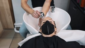 An experienced hairdresser creates a hairstyle for a beautiful young woman after cutting and coloring her hair. She is wearing protective face mask as protection against virus pandemic. - Powered by Shutterstock - Get 15% off with code: PIKWIZARD15