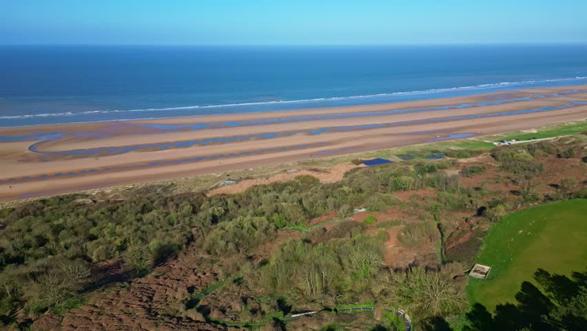 Historic Omaha Beach, Normandy, wide golden sandy beach, sea, ocean, famous D-Day landing site, France. Aerial forward, sky for copy space
