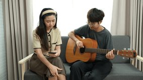Young lesbian couple playing guitar and singing happily together at home - Powered by Shutterstock - Get 15% off with code: PIKWIZARD15