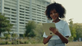 Portrait of pretty African American woman using tablet computer against office building on street. Female student scrolls internet in touchpad device on city square - Powered by Shutterstock - Get 15% off with code: PIKWIZARD15