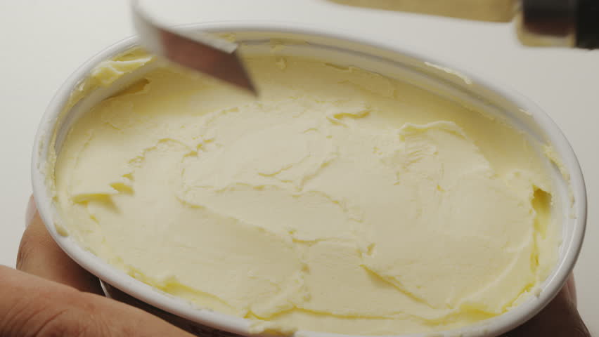 Butter is scraped off with a special butter knife from a pack of butter into a recognizable shape.