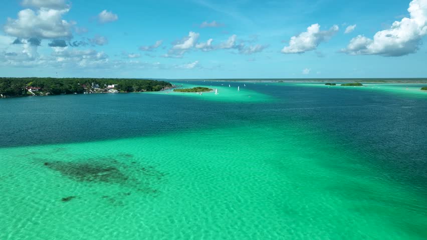Boats sailing on emerald green lagoon under blue sky, Lagoon of seven colors, Bacalar, Quintana Roo, Drone shot