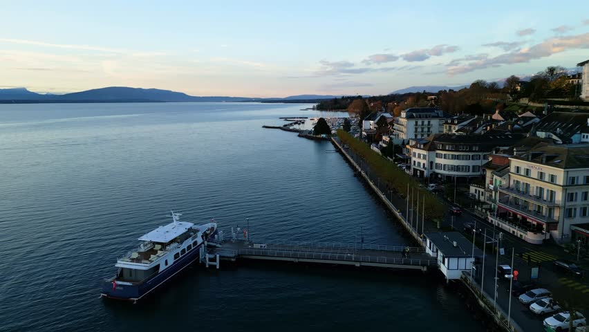 Pull out drone shot of boat at Nyon port at sunrise on Lake Geneva in Canton of Vaud Switzerland