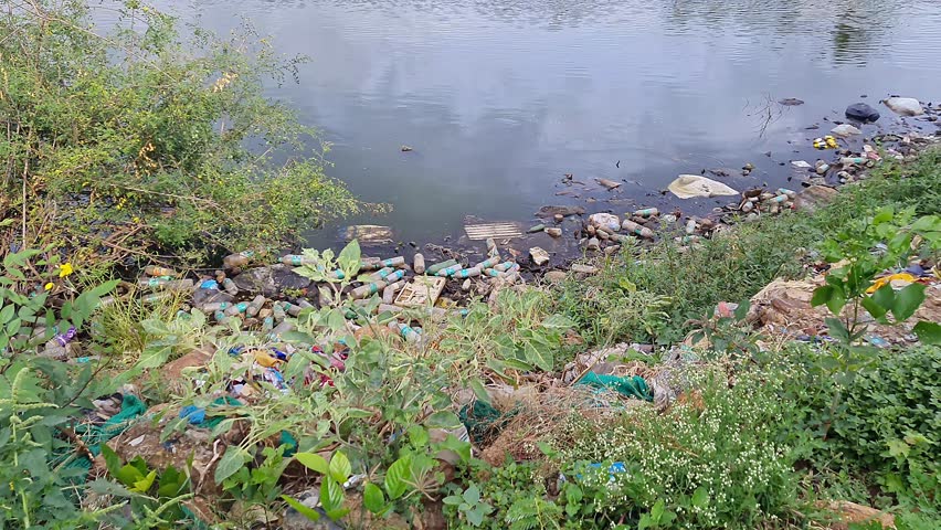A rural lake filled with plastic litter and dirty water, highlighting serious environmental pollution and lack of proper waste management. awareness campaigns.global ecological issues
