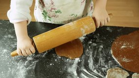 Child is rolling gingerbread dough in the kitchen, family bonding, baking cookies for christmas, holiday tradition, view from above, flour on the black table - Powered by Shutterstock - Get 15% off with code: PIKWIZARD15