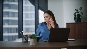 Busy manager talking cellphone browsing website at laptop in modern office. Confident businesswoman calling writing notes in notebook at workplace. Elegant woman employee discussing online project. - Powered by Shutterstock - Get 15% off with code: PIKWIZARD15