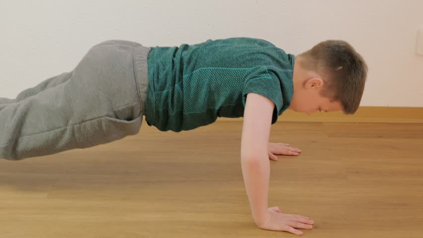 10-year-old boy does push-ups at home, strengthening muscles and improving endurance, home gym, physical education, workout session, indoor fitness, sport exercises
