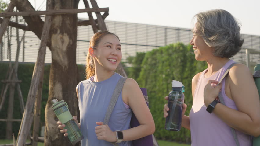 Young adult child and mature middle age old mum public park walk workout with yoga mat water bottle. Love health care older mom asia elder people happy protect aging life enjoy sport club class active