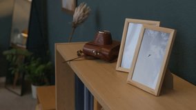 Vintage leather camera case, two framed photos and books on wooden shelf in cozy minimalist living room - Powered by Shutterstock - Get 15% off with code: PIKWIZARD15