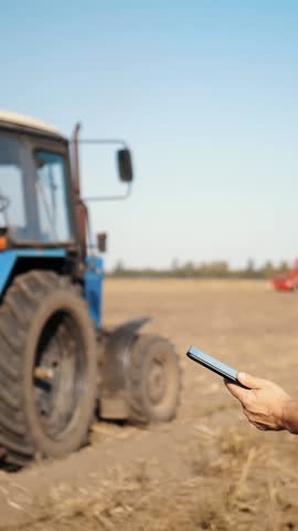 Farmer is using digital tablet. on farm field, near tractor, on farm machinery backdrop. smart farming. farming technologies