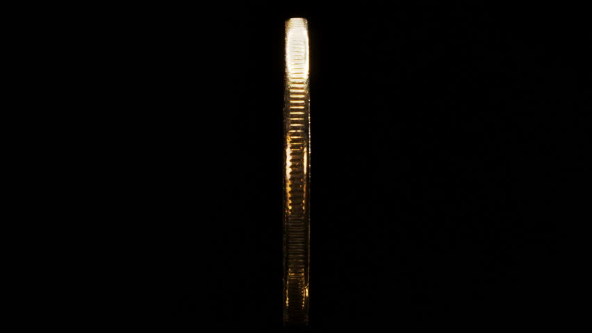 Physical golden plated coin with the Bitcoin logo spins around its axis on black background.