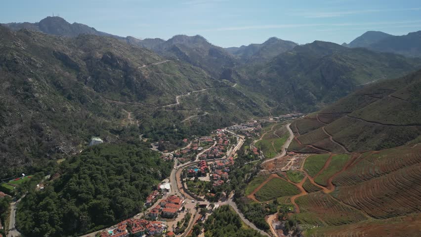 Drone view over Icmeler valley, Turkey. Mountain road snakes upward. Green hills of Turkiye unfold. Winding paths tell stories of ancient travel.