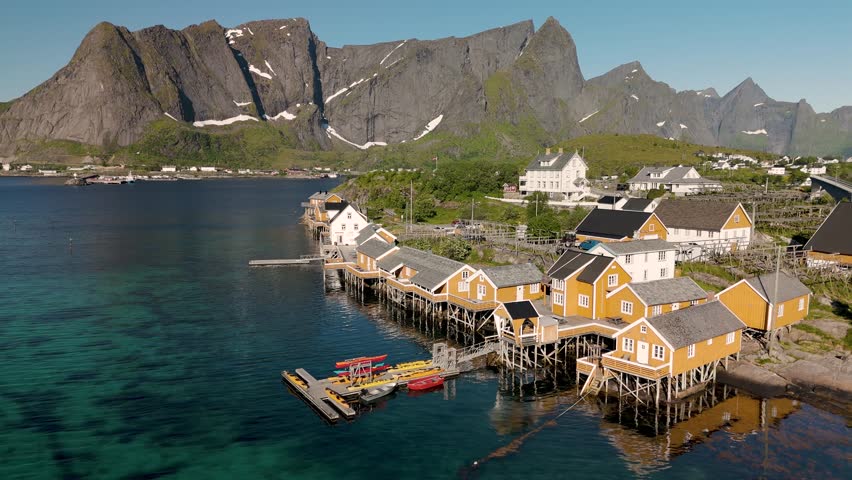 A stunning coastal village in Norway showcases vibrant orange cabins sitting atop stilts above crystal-clear waters. Sakrisoy, Moskenes, Lofoten islands. Norway.