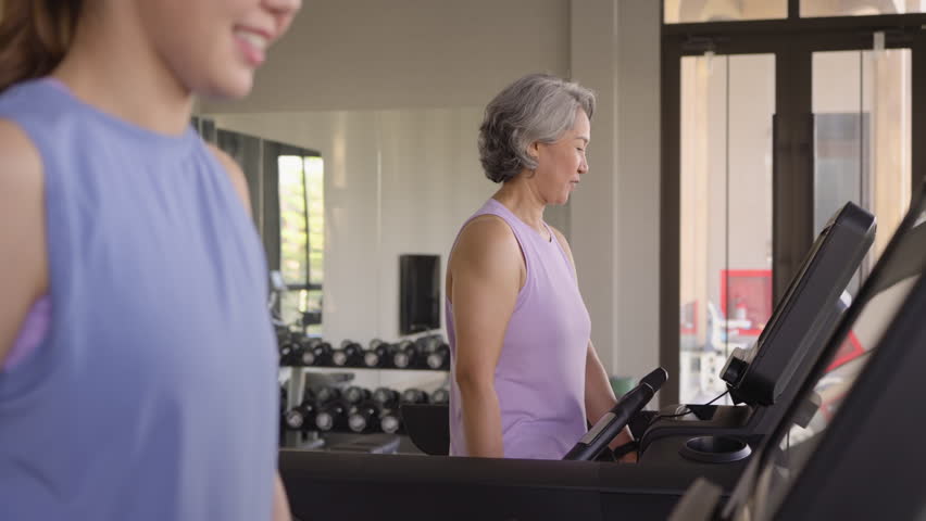 Young active adult child and mature middle age old mum run walk advice workout at gym. Love mental health care older retired mom asia elder people happy protect aging life balance enjoy sport club.