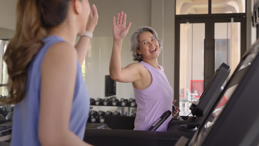 Young active adult child and mature middle age old mum run walk advice workout at gym. Love mental health care older retired mom asia elder people happy protect aging life balance enjoy sport club.