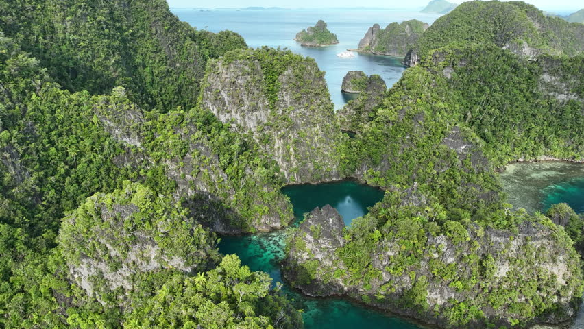 A set of rugged limestone islands rise from the ocean in Misool, Raja Ampat, Indonesia. This area is known as the heart of marine biodiversity and is a popular destination for diving and snorkeling.