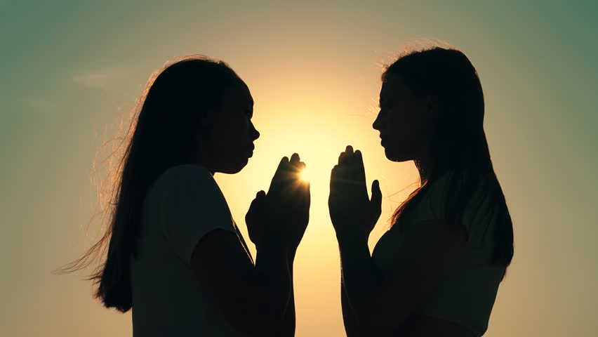 Morning prayer of girls in outdoors. Freedom of religion. Young women praying at sunset, silhouette. Path of soul to God through prayer. Christian prayer nature. Era of mercy kindness love. Girl relax