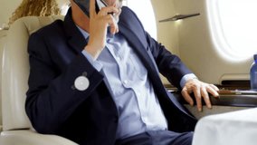 Business CEO speaking on smartphone in private jet, with digital music phone icons overlaying cabin. Corporate, luxury, technology, executive, travel, connectivity, sophistication - Powered by Shutterstock - Get 15% off with code: PIKWIZARD15