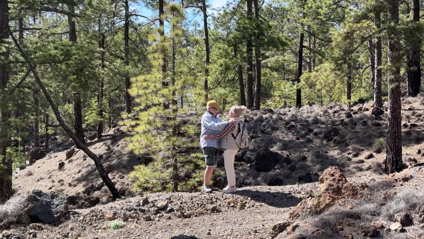 Retired couple walking in lush woods on mountain path, healthy seniors enjoying outdoor leisure, emotional connection, relaxing vacation and mindful aging in beautiful natural environment