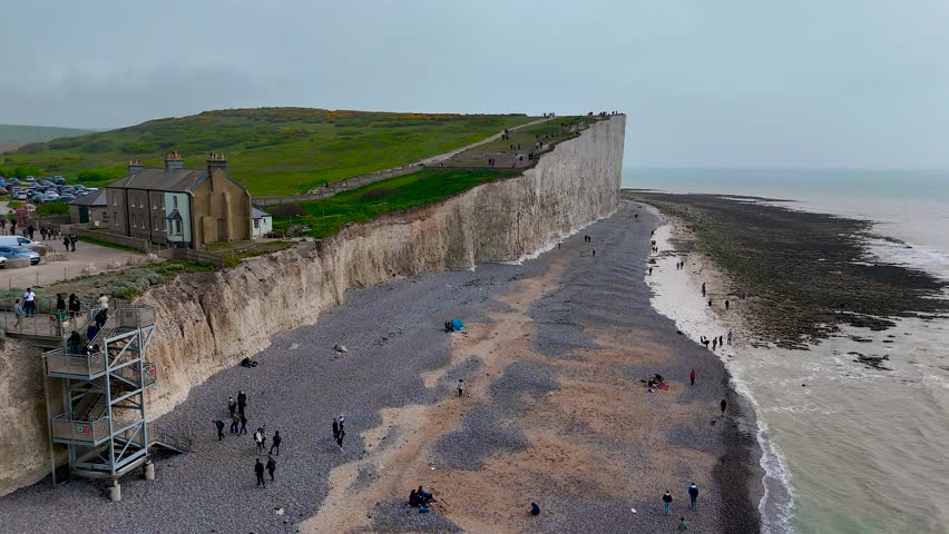 Panoramic view of the iconic white chalk cliffs of England with a stony beach and turquoise sea, ideal for travel, tourism, nature, and adventure concepts in commercial campaigns