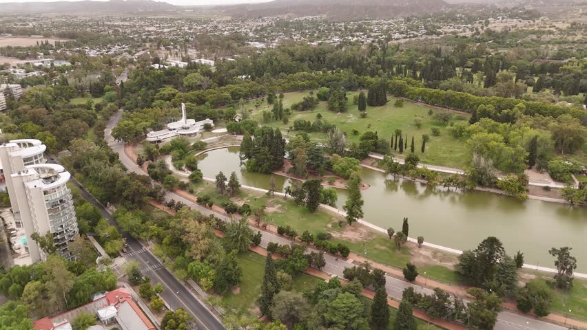 Drone footage shows the lake (Lago del Parque) within Parque General San Martín, Mendoza, Argentina. Clear 4K 60fps aerial reveals the water and surrounding park greenery