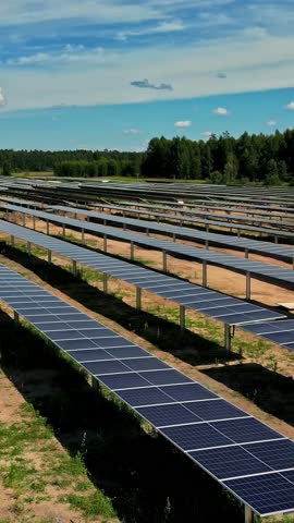 Vertical shot of solar park, solar panel for renewable energy, future power with sunlight, industry, cloudy sky with copy space, green trees around