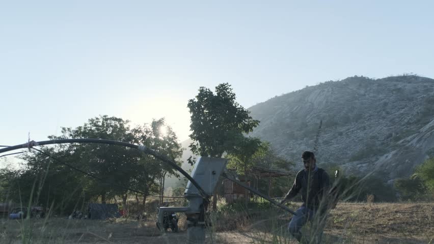 Hiker drinking water from handpump in rural areas of India with sun shining brightly.