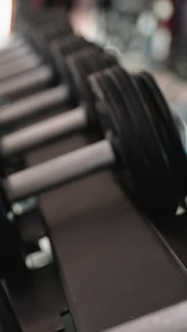 Close-up view of a man s hand grabbing a dumbbell from a weight rack in a modern gym