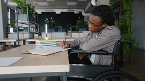 Focused student in wheelchair writing during exam prep - Powered by Shutterstock - Get 15% off with code: PIKWIZARD15