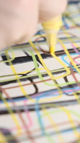 Man drawing lines with marker with right hand in dimly lit room