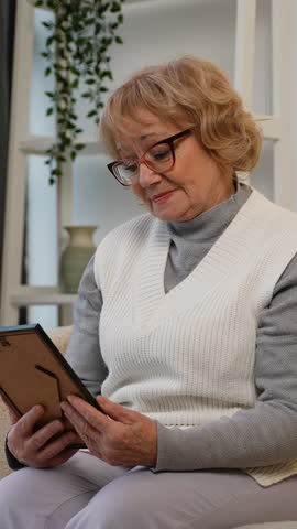 Sad elderly woman looking at an old photo with nostalgia