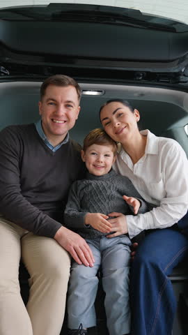 Happy family sitting in their new car trunk at dealership