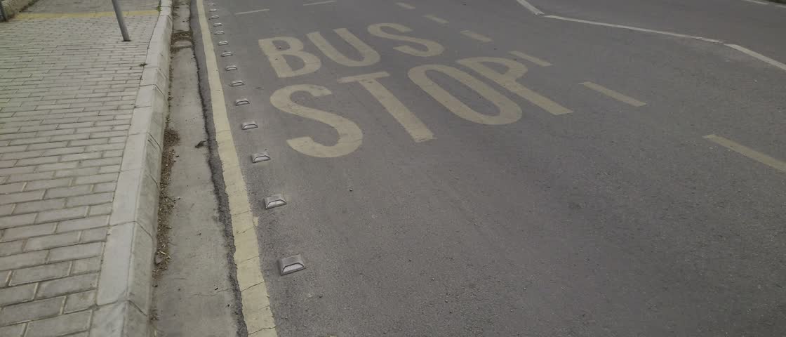 Stop and wait for the bus at a quiet road intersection in the heart of the city during a cloudy afternoon