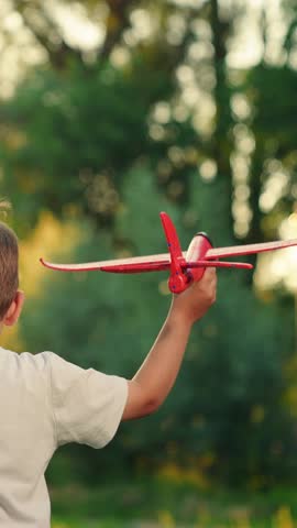 Happy child is playing toy airplane in park. Child is playing pilot in open air. Little boy with an airplane runs park. Child fly, holiday. Family vacation in summer outdoors. Children play in nature