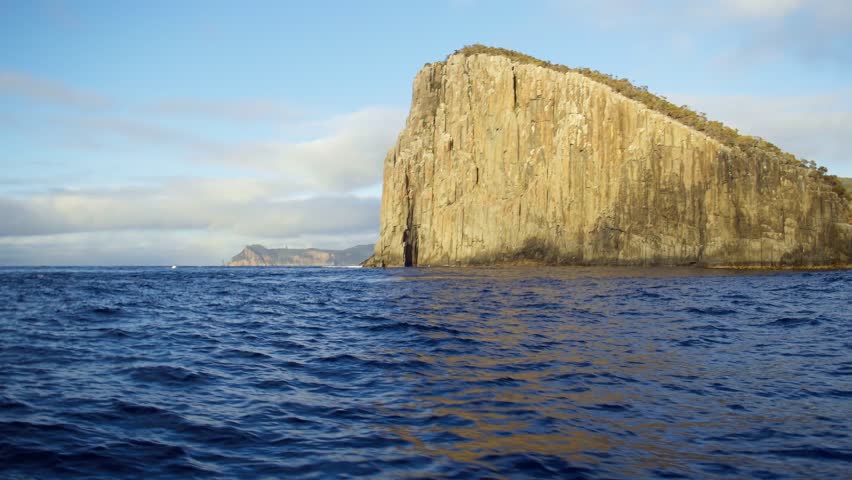 Sheer cliffs rise from the deep blue Tasman Sea, forming a dramatic and untouched stretch of Tasmania’s southern coastline, captured from the water in 4K.
