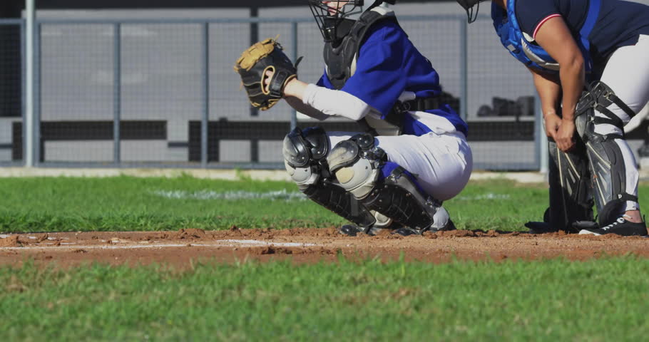 Female catcher and umpire crouching behind home plate on baseball field with mitt mask and fence. Athletic, sports, competition, teamwork, outdoor, vibrant, action