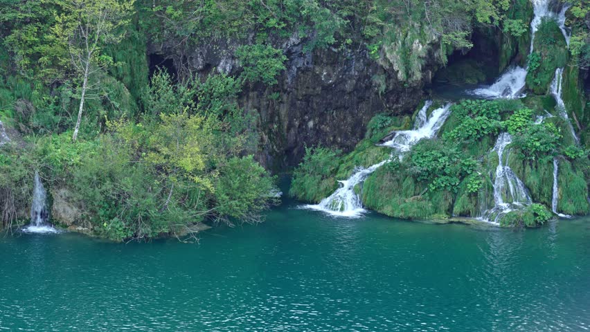 Beauty of waterfalls in nature. Lake reflections of a stunning waterfall. Relaxing to the sound of rushing waterfalls. Waterfall and mountain landscapes. A waterfall oasis in a national park.