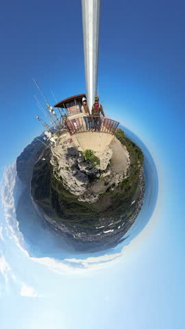 Vertical video. Tiny Planet View of a Couple on an Observation Deck at a Mountain Summit Surrounded by a Panoramic Landscape with the Sky Wrapping Around Them