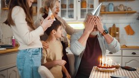 Funny moment of balloon bursting, falling on birthday cake candles as grandpa makes a wish, preparing to blow and blow out the candles, family celebrating grandpa's birthday together in the kitchen. - Powered by Shutterstock - Get 15% off with code: PIKWIZARD15