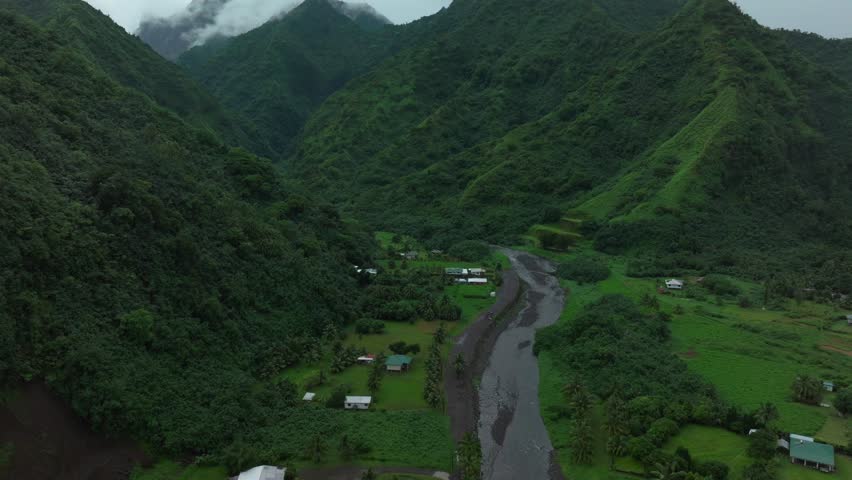 Tahiti French Polynesia Teahupoo aerial drone raining fog mountain peaks river morning grey gray season wet green Point Faremahora village town South Pacific Mount Tohivea island forward pan up motion