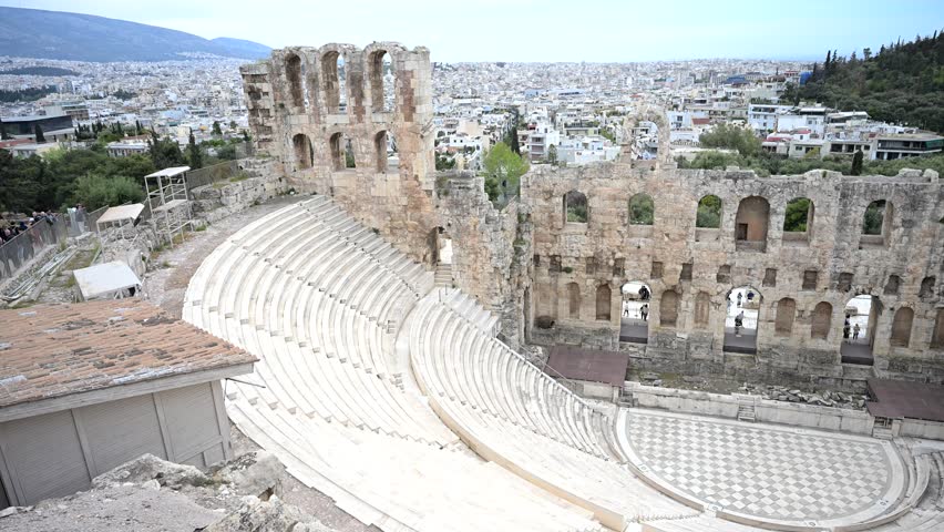 Historic Odeon of Herodes Atticus, an ancient stone theatre set against the modern cityscape of Athens.