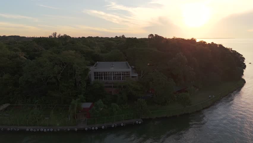 Aerial view of a party room surrounded by a green environment, with an amazing sunset over the Paraná River in the background, Misiones, Posadas.