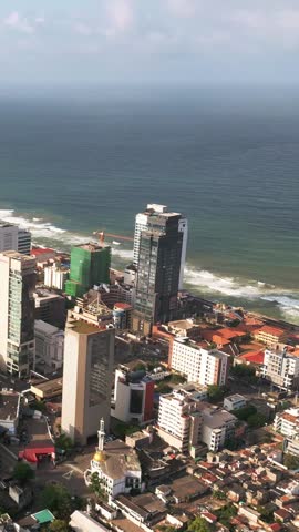 Cinematic vertical panning aerial revealing Colombo s city centre skyline, luxury towers, and the oceanfront -perfect for tourism, urban lifestyle, and real estate promotional use.