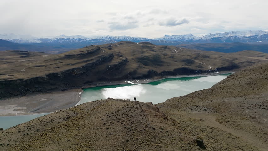 Aerial view of a lone hiker admiring the breathtaking landscape in Torres del Paine, Southern Patagonia.Circle Dolly Shot