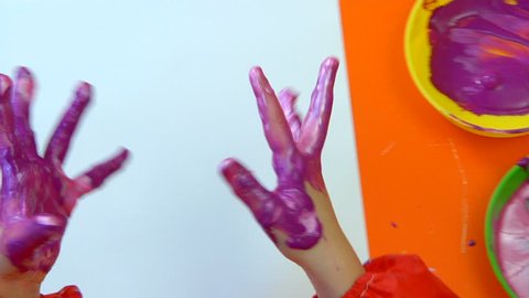 Overhead shot of a child making handprints with paint