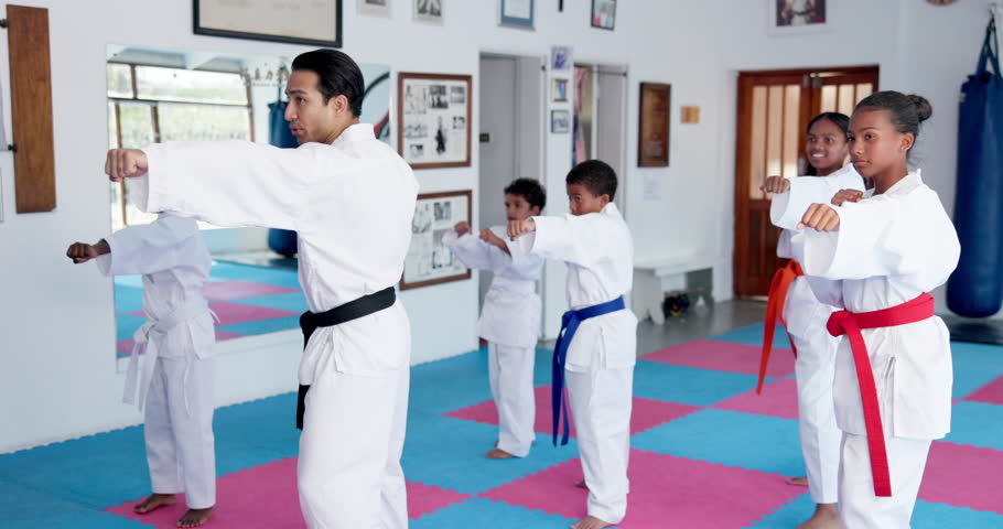 Teaching karate, children and group exercise in dojo for sport, fitness lesson or self defense class. Students, instructor and practice martial arts with man for workout, learning and kids training