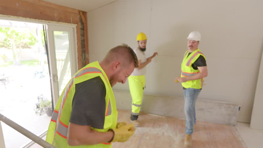 Dedicated construction crew, all wearing bright safety vests and helmets, is engaged in injury worker situation at renovated indoor space, first aid needed