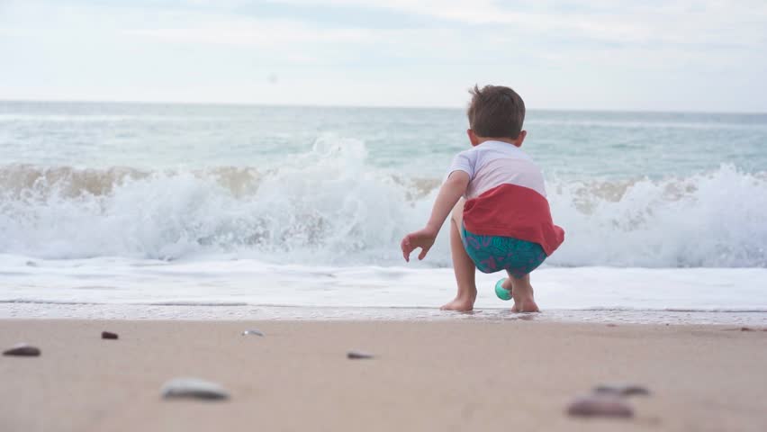 Young boy playing by the sea shore at sunset